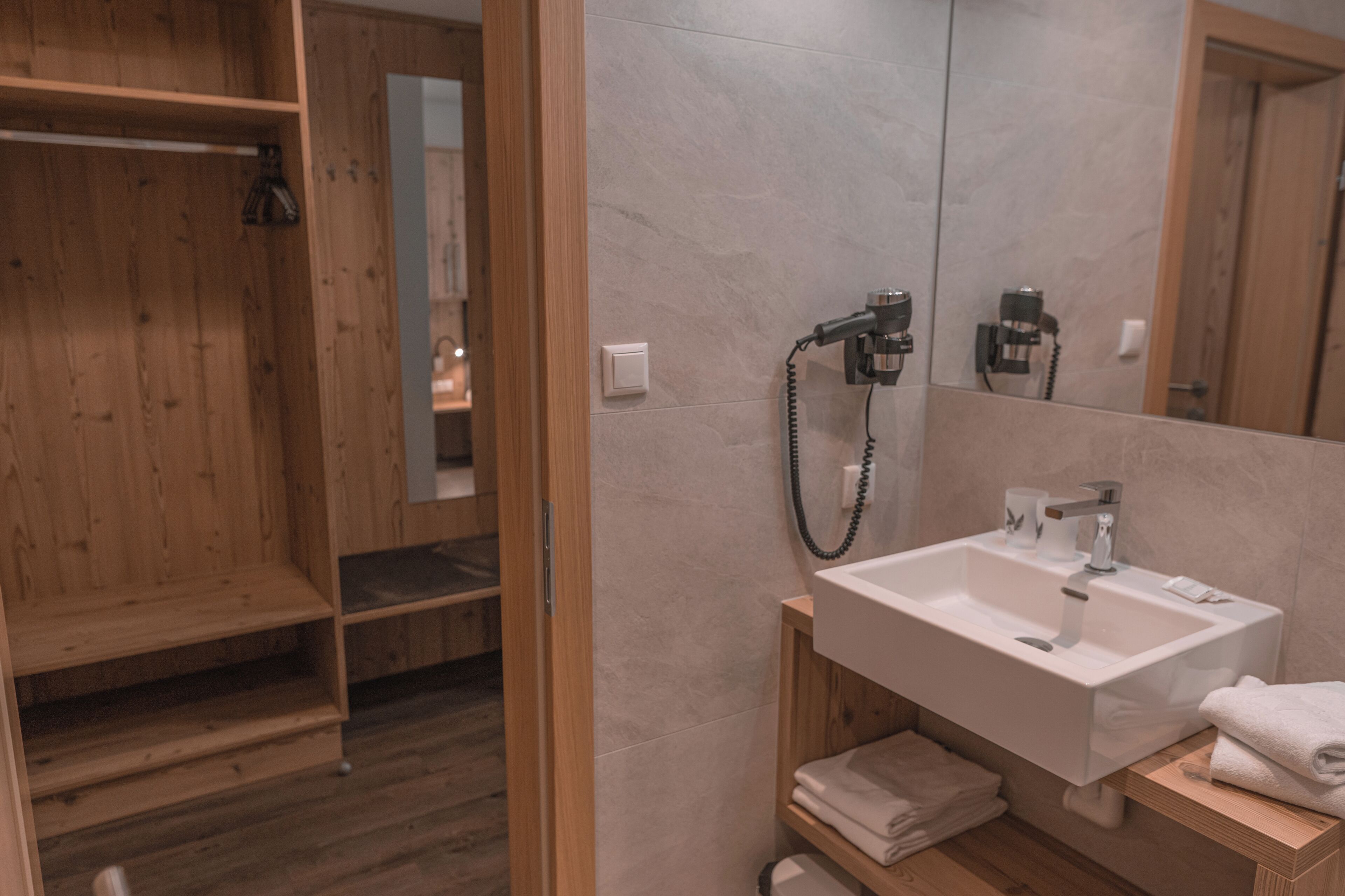 A modern bathroom with a wooden shower enclosure, a white sink, and a mirror.