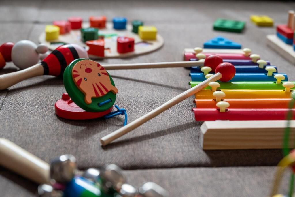 Un xylophone en bois avec des lames colorées et des baguettes.