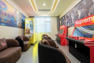 Un espacio de juegos con máquinas de arcade, asientos cómodos y arte mural colorido.