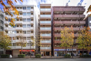 A multi-story building with balconies, a uniform shop, and a Lawson convenience store. - Dash Living Shinjuku (Tokyo)