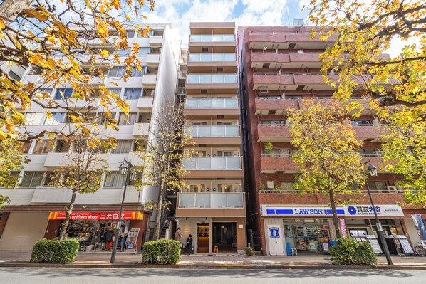 A multi-story building with a uniform shop on the ground floor, a Lawson convenience store, and a visible entrance. - Dash Living Shinjuku (Tokyo)