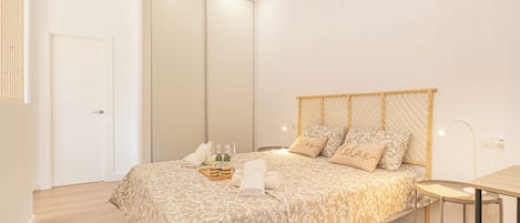 Een slaapkamer met een bed, nachtkastje en een tafeltje met een lamp.