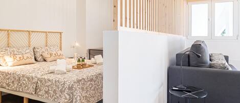 Een moderne slaapkamer met een bed, nachtkastje en een grijze bank.