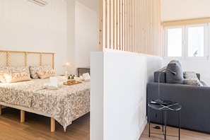A modern bedroom with a bed, bedside table, and a grey sofa. - Calahonda Beach (Mijas)