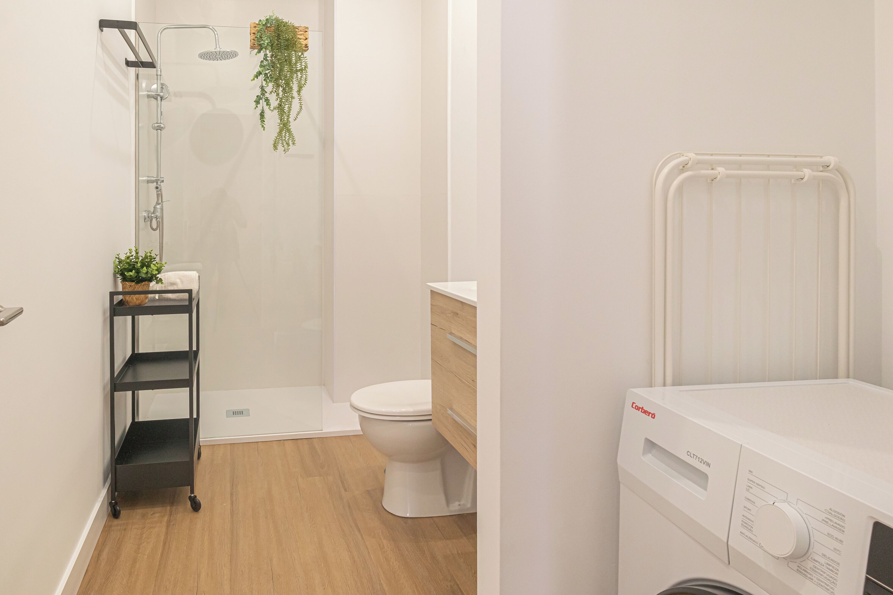 A modern bathroom with a shower, toilet, and a white washing machine.