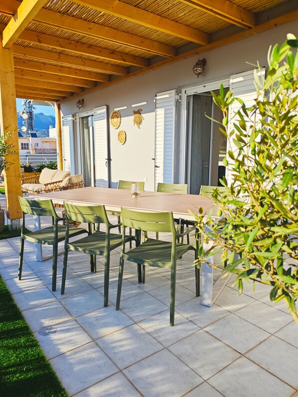 Eine Außenpatio mit einer Holz-Pergola, einem Esstisch mit Stühlen und Blick auf die Stadt.
