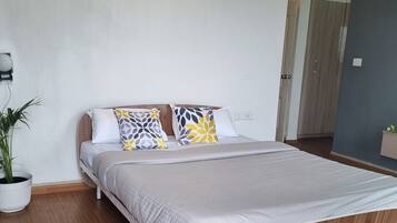 Ein modernes Schlafzimmer mit einem hölzernen Bett, weißer Bettwäsche und einer Zimmerpflanze.