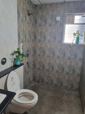 Ein Badezimmer mit Dusche, Toilette und einem Fenster mit Pflanze.