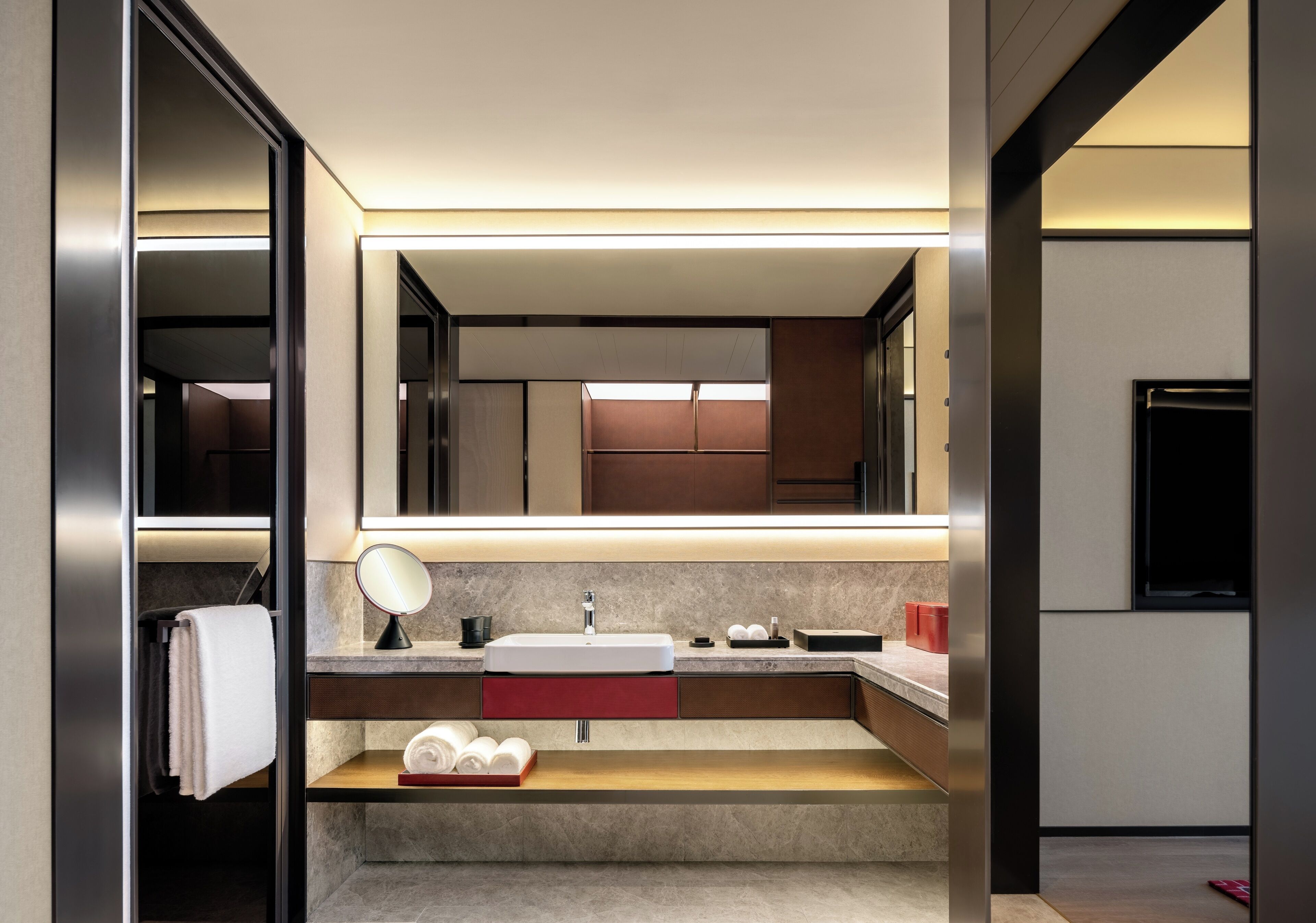 A modern bathroom with a large mirror, a sink, and a towel rack.