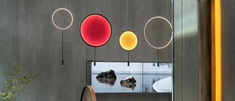 Et moderne interiør med en stor, rund rød lampe, en lille gul lampe og en skærm på en disk.