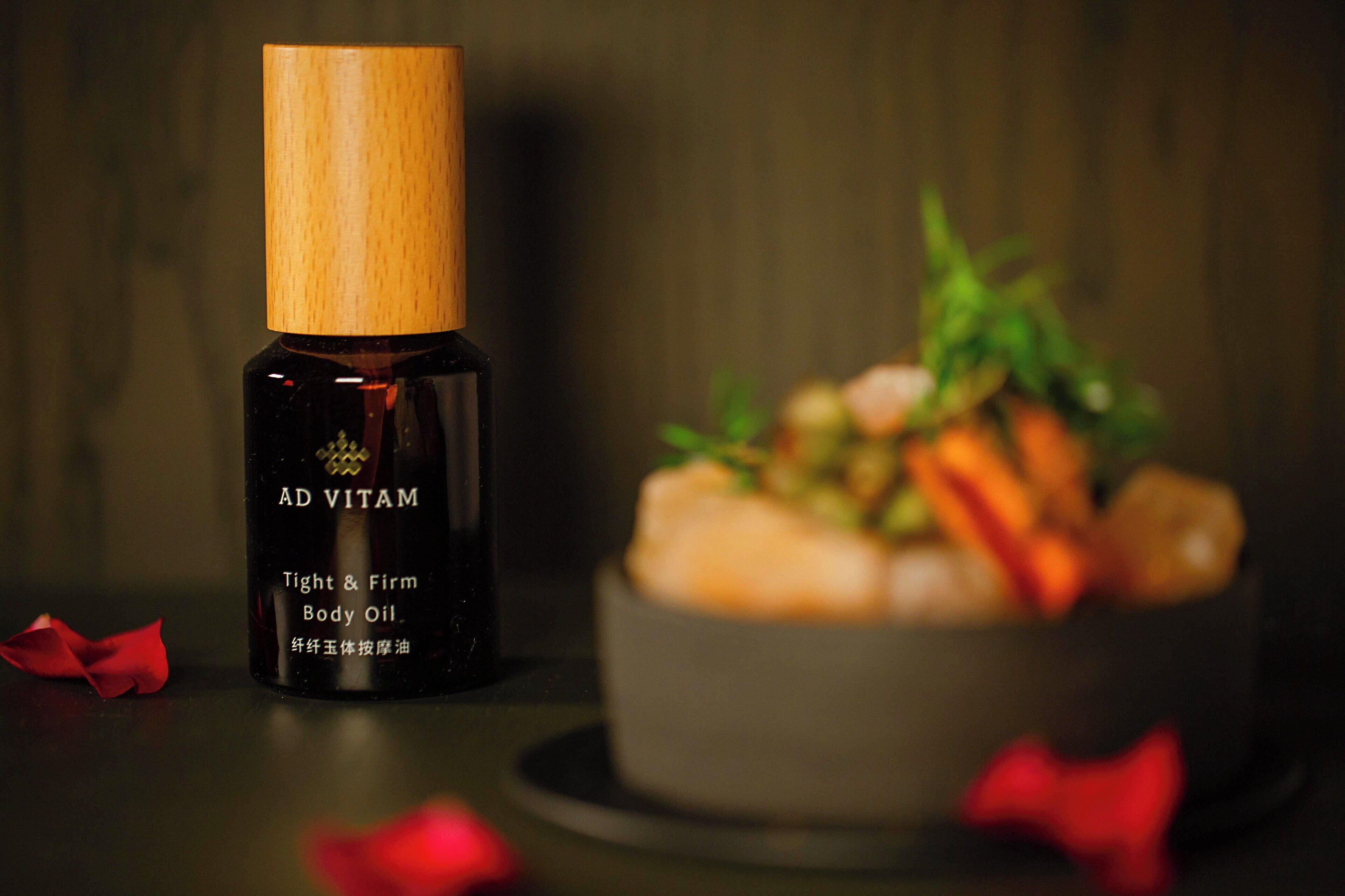 Eine Flasche Ad Vitam Tight & Firm Body Oil neben einer Schüssel mit Speisen.