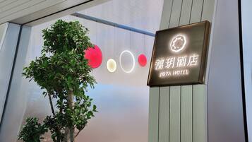 A hotel sign with illuminated circles and a tree in front.