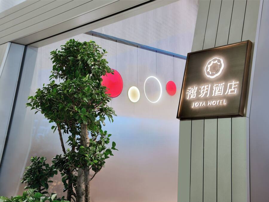 A hotel sign with illuminated circles and a tree in front.