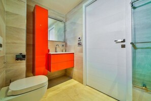 Een moderne badkamer met een wit toilet, een rode wastafel en een grote spiegel.