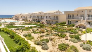 A coastal hotel with multiple balconies, a pool area, and a landscaped garden. - GuestHost - Comfortable 40 sqm apartment, perfect for 4 people, located on the ground floor.The property is located inside the Borgo 81 Residence, a short distance from Marzamemi, and offers a quiet and well-served context, with a shared swimming pool, c (Pachino)