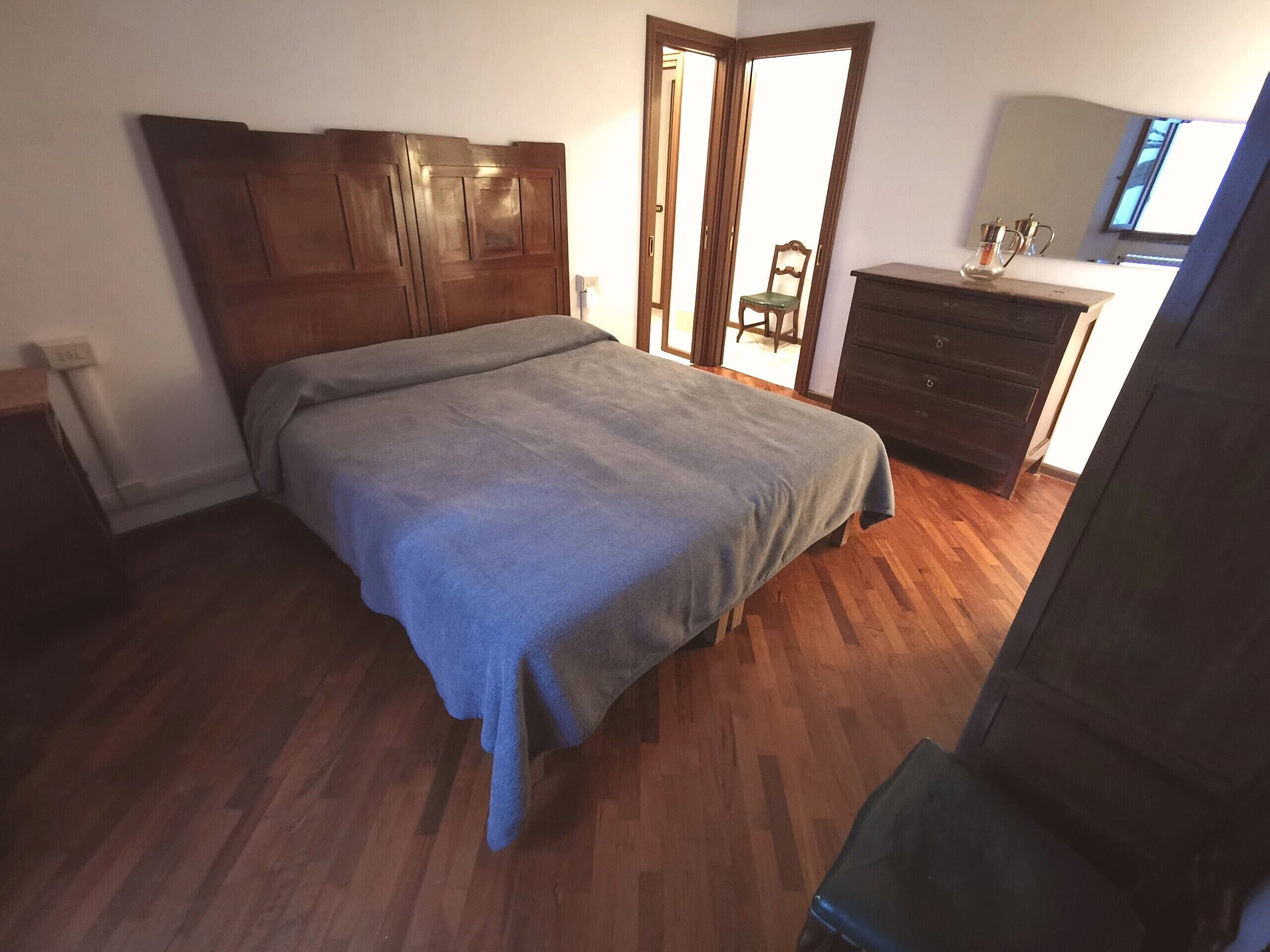 A bedroom with a wooden bed, a dresser, and a chair.