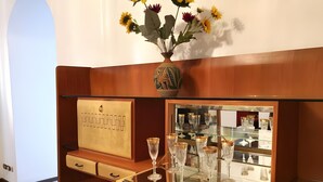 Un meuble en bois doté d’une vitrine où sont exposés des verres en cristal et un vase rempli de fleurs.