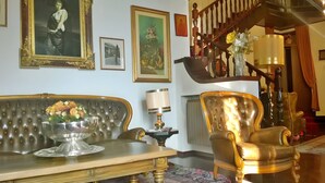 Une pièce comprenant un canapé, un fauteuil, une table avec un vase de fleurs, une lampe et un escalier.