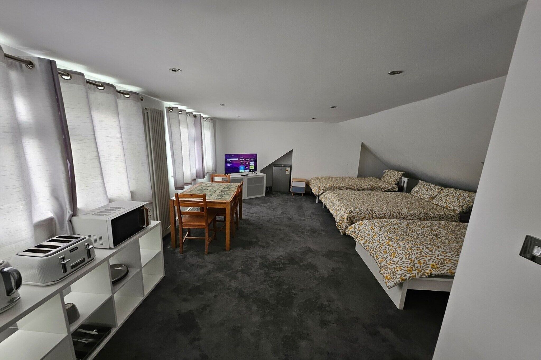 Een kleine slaapkamer met een bed, een bureau en een stoel.
