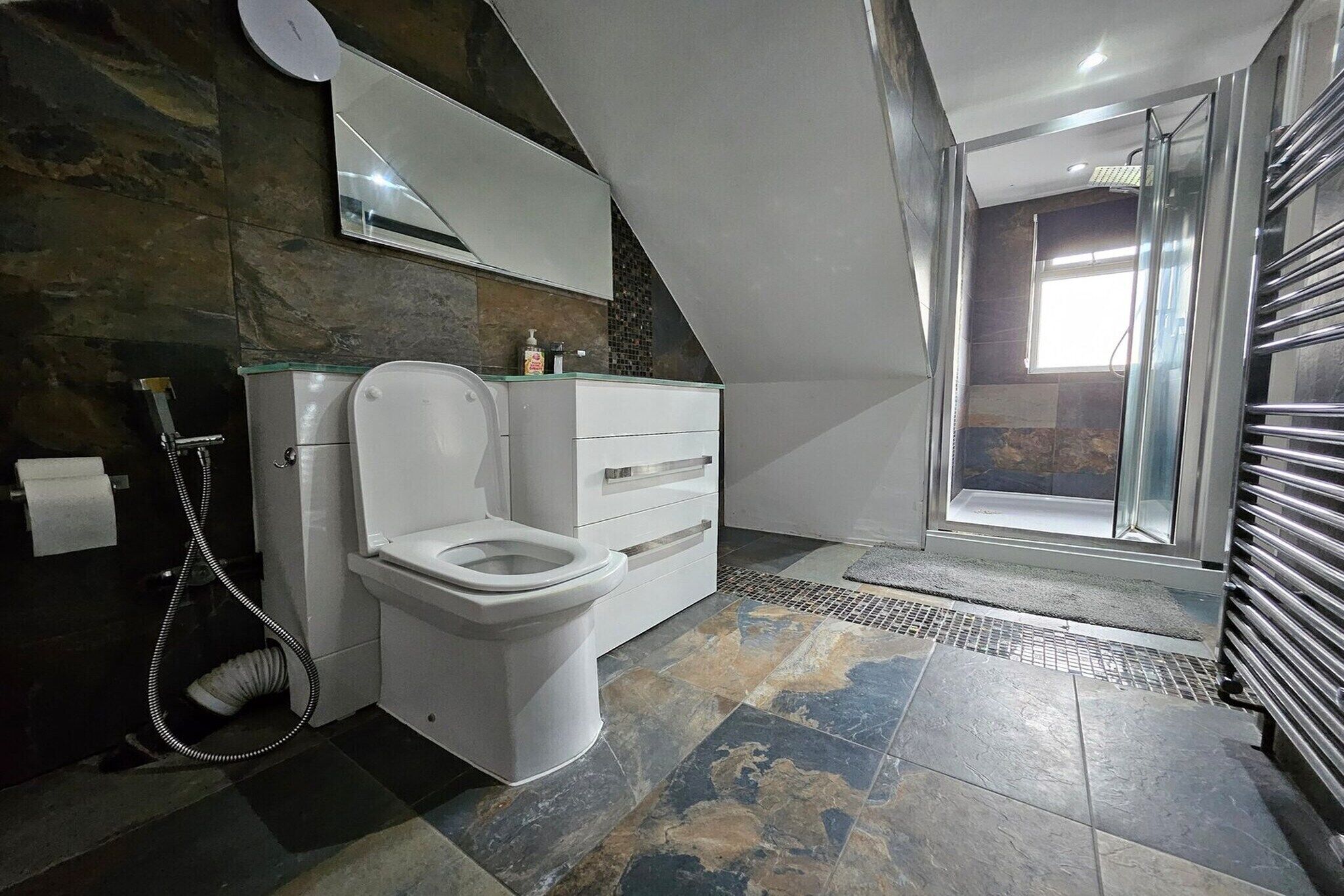 Ein modernes Badezimmer mit Toilette, Waschtisch und Duschbereich.