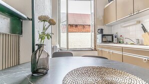 A kitchen with a large window, a vase with flowers, and a woven placemat on the table.
