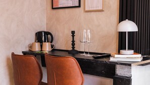 A modern kitchen with a black countertop, two brown leather chairs, a coffee maker, wine glasses, and a white lamp.