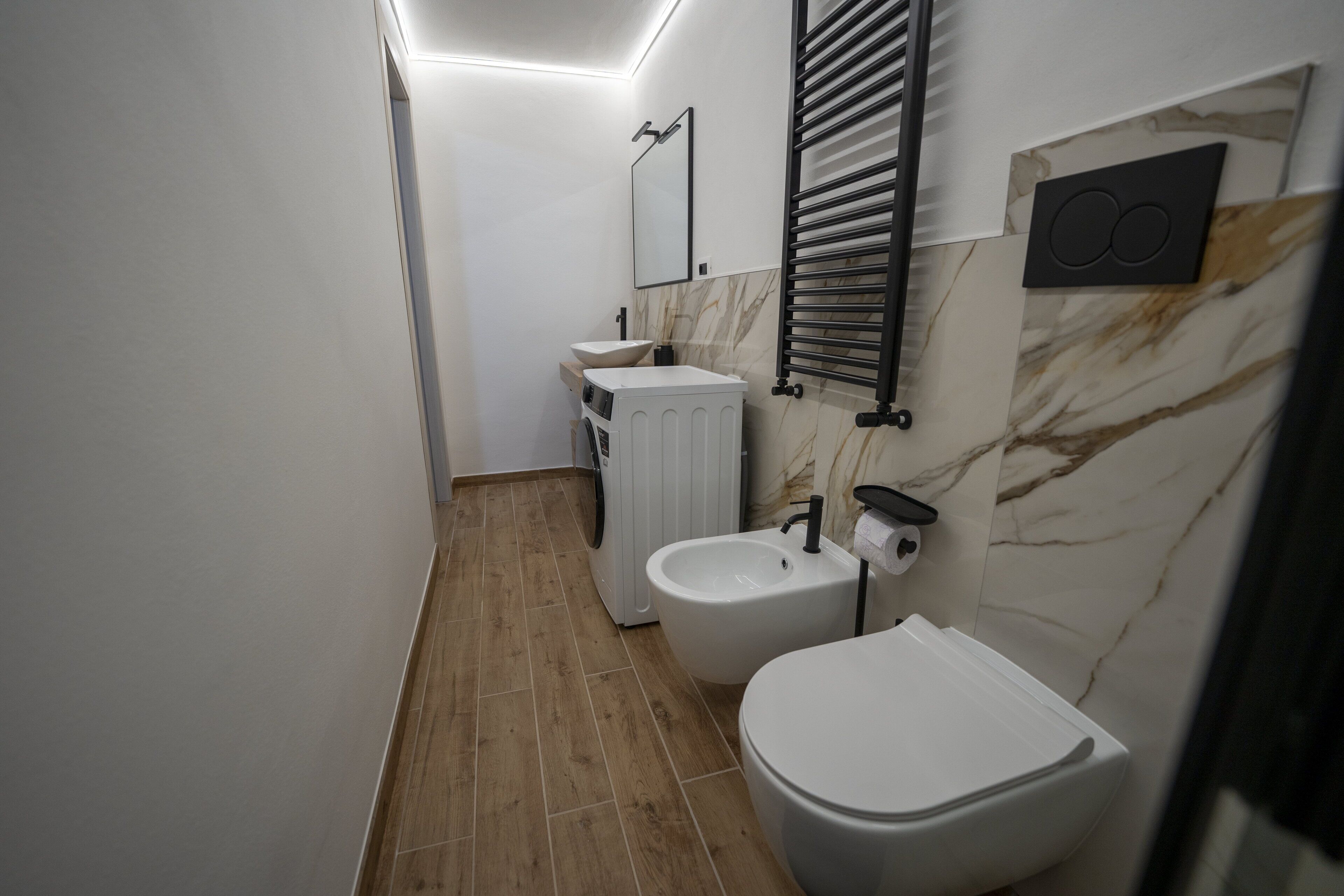 Ein modernes Badezimmer mit Toilette, Bidet und Waschmaschine.