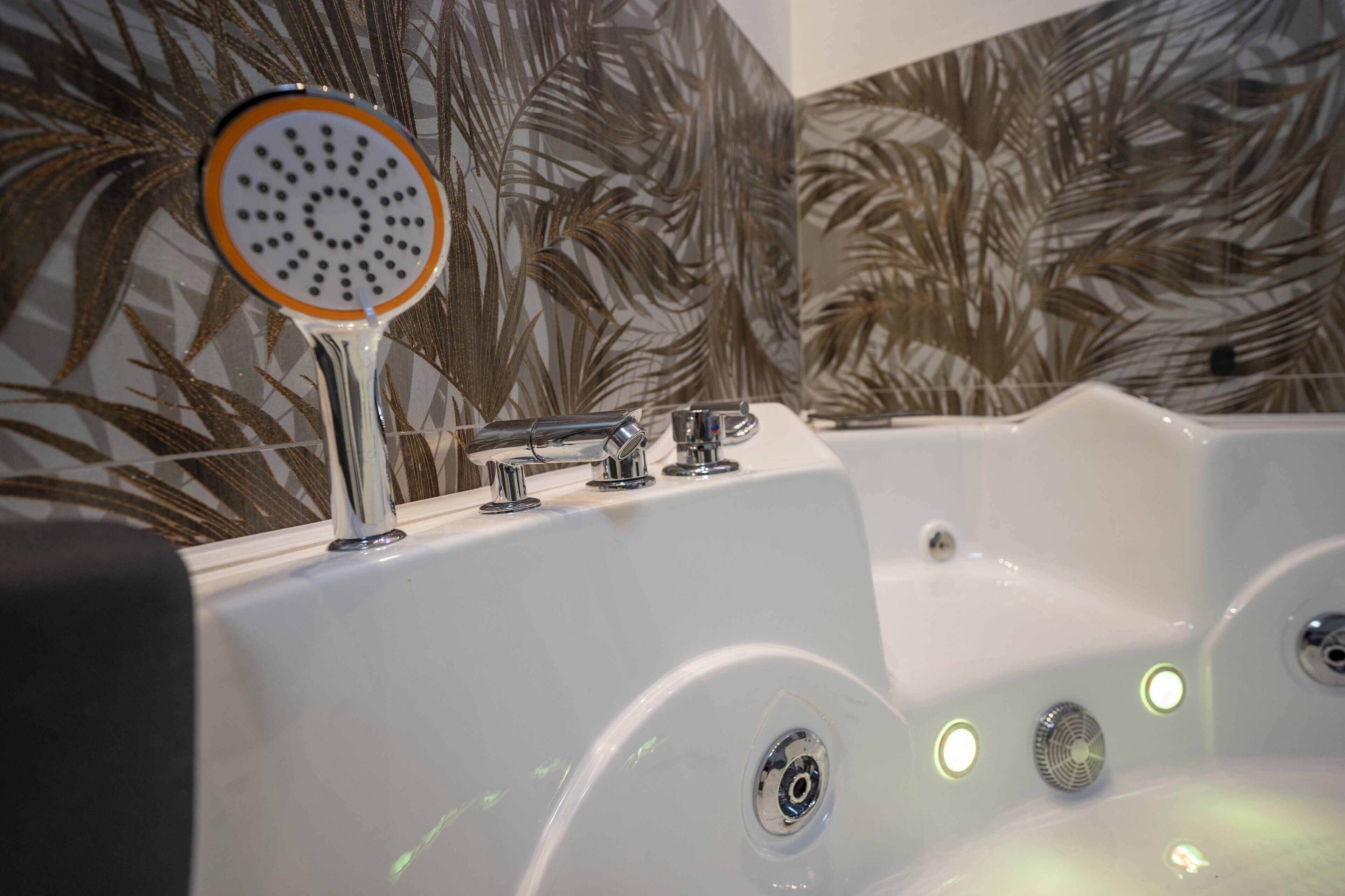 A white bathtub with a handheld showerhead and multiple faucets.