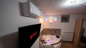 A modern bathroom with a large bathtub, a wall-mounted air conditioner, and a neon sign. - Love Nest Siena: Romantic Suite with SPA & Jacuzzi (Toscana)