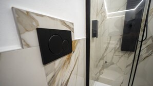 A modern bathroom with a marble wall, a black speaker, and a glass shower enclosure. - Love Nest Siena: Romantic Suite with SPA & Jacuzzi (Toscana)