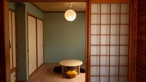A traditional Japanese room with sliding doors, a tatami mat floor, a low table, and a hanging paper lantern.