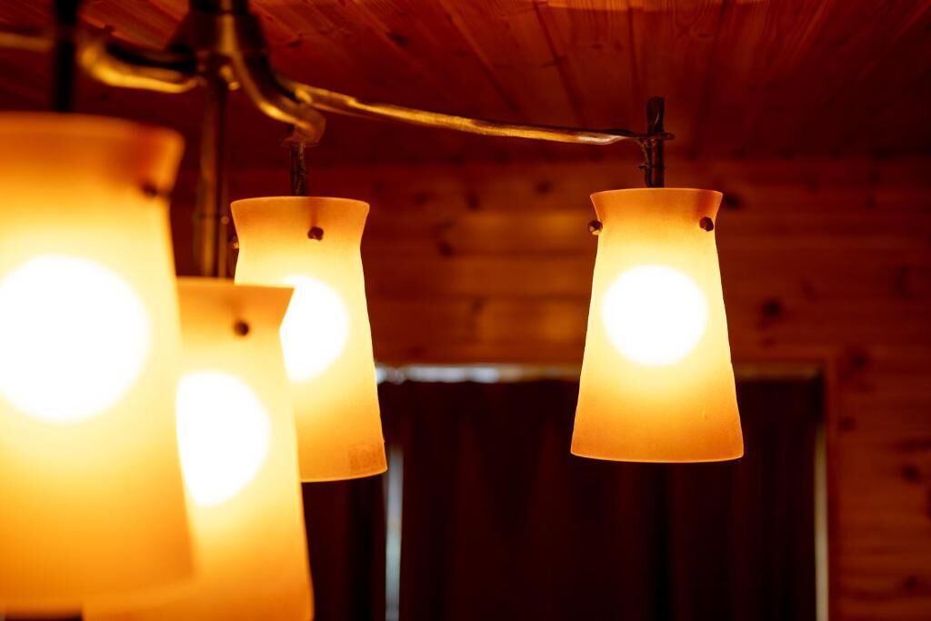 A close-up of three hanging lamps with a warm glow, set against a wooden wall background.