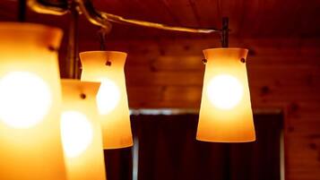 A close-up of three hanging lamps with a warm glow, set against a wooden wall background.
