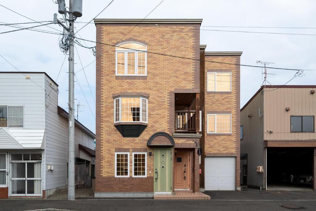 A two-story brick building with a green door, a small balcony, and a garage.
