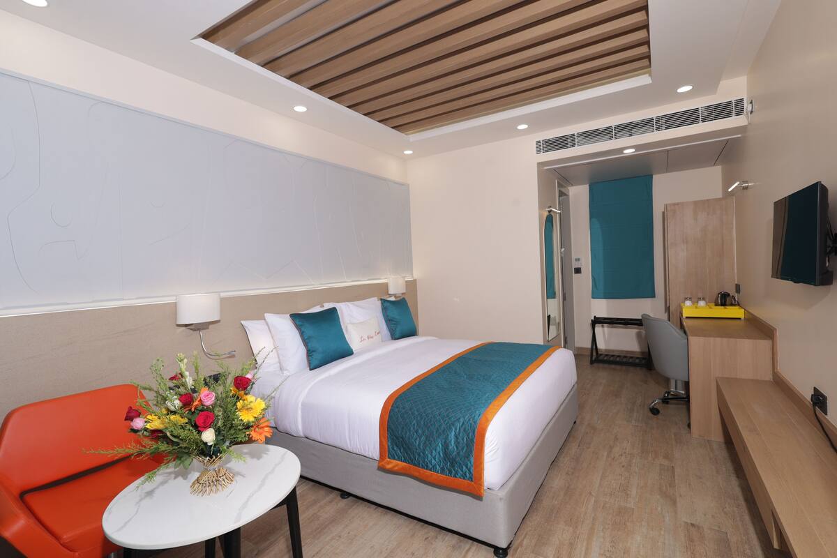 A modern hotel room with a bed, a desk, and a chair.