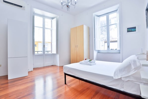 A bedroom with a bed, a wardrobe, and a window.