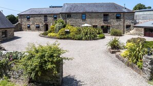 A stone building with a gravel courtyard, a small garden, and a visible entrance.
