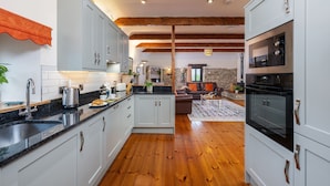 A modern kitchen with granite countertops, white cabinets, and a wooden ceiling.