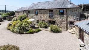 Un bâtiment en pierre avec une allée gravillonnée, une petite terrasse avec une table et des chaises, et une enseigne indiquant « Wheat Jame ».