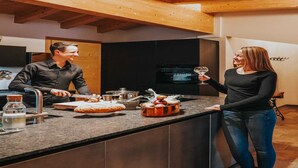 Una cocina moderna con techo de madera, una isla grande con fregadero y un televisor montado en la pared.