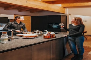 Una cocina moderna con techo de madera, una isla grande con fregadero y un televisor montado en la pared.