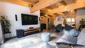Un moderno salón con un televisor de pantalla plana grande, un sofá gris y un techo de madera.