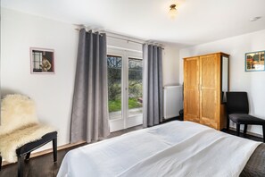 A bedroom with a bed, a chair, a wardrobe, and a window with curtains. - Apartment 60 qm, 1 Schlafzimmer, Bergblick, Terrasse, WLAN (Mühlenbach)