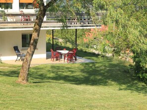 A patio with outdoor furniture, a tree, and a building with a covered area. - Apartment 60 qm, 1 Schlafzimmer, Bergblick, Terrasse, WLAN (Mühlenbach)