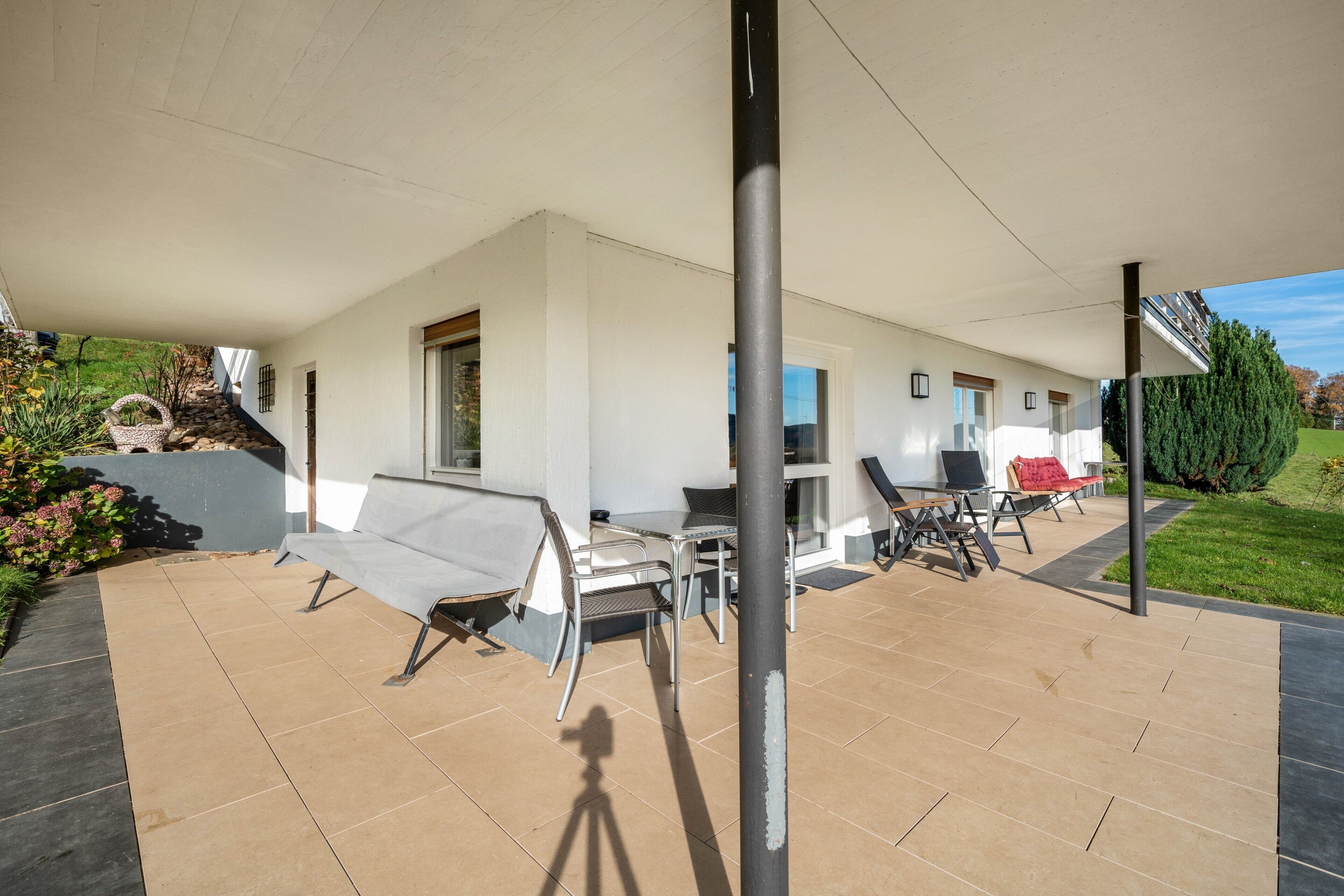A covered patio area with outdoor seating, a table, and a chair.