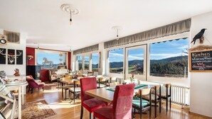 Ein Essbereich mit roten Stühlen, einem Holztisch und großen Fenstern mit Blick auf die Landschaft.
