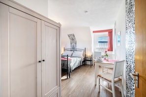 A bedroom with a bed, bedside table, and a window with curtains.