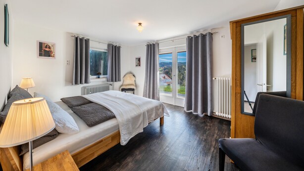 Ein Schlafzimmer mit Bett, Nachttischlampe und Blick aus dem Fenster.