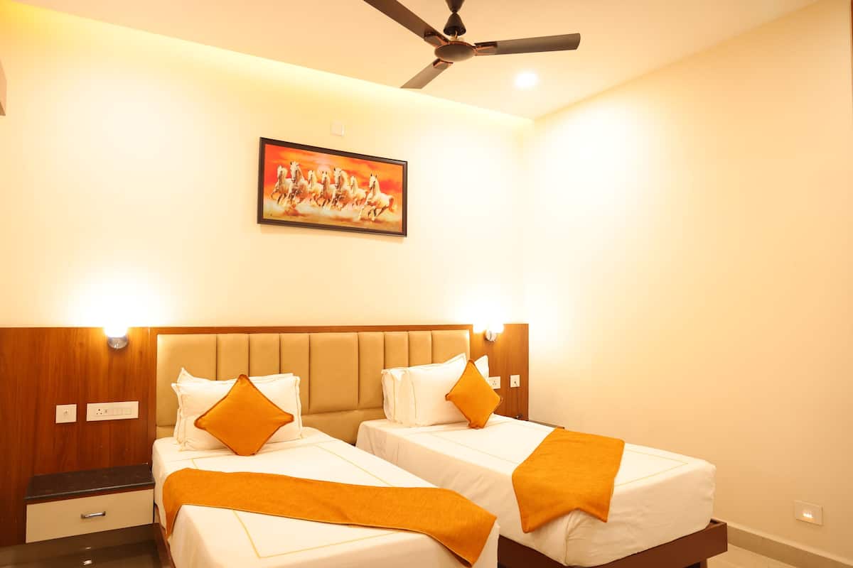 Quarto de hotel com duas camas, um ventilador de teto, um quadro e uma mesa de cabeceira.