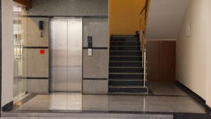 A modern elevator with a glass door, a phone, and a fire alarm. - Nanda Mohan Residency (Tirupati)